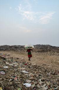 Rear view of man standing on garbage