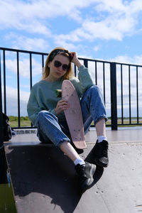 Portrait of young woman sitting on railing