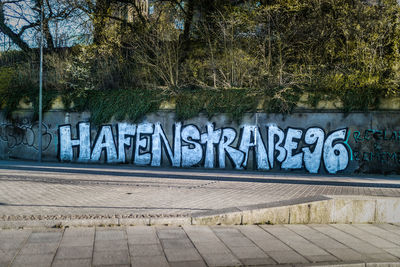 Text on wall by footpath