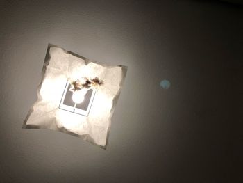 High angle view of illuminated lamp on table against wall