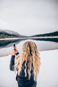 Woman photographing on snow covered landscape