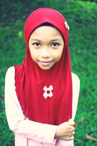 Portrait of smiling girl wearing hijab while standing on grassy field