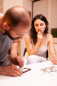 Side view of young woman using mobile phone while sitting at home