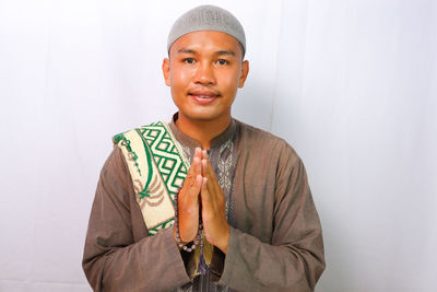 A muslim man is smiling while raising his hand