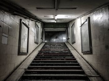 Steps amidst paintings on wall in illuminated corridor