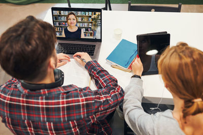 Students learning in library. young man having video class on laptop. students studying for exams