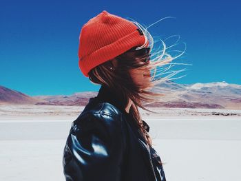Woman with umbrella standing against sky