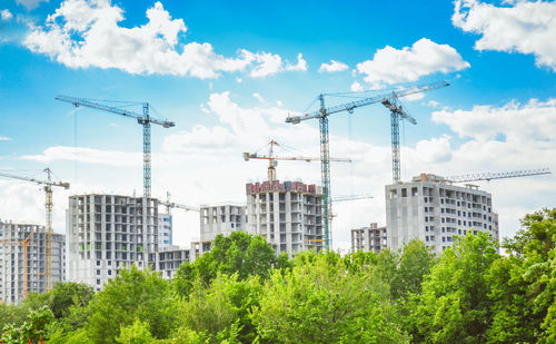 Construction of high-rise buildings. city landscape. green trees. blue sky and white clouds.