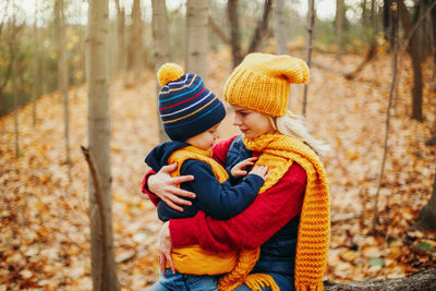 Rear view of mother and son in forest during autumn