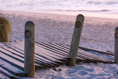 Wooden posts on beach during sunset