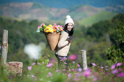 Smiling woman carrying flowers in basket