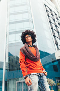 Low angle view of thoughtful fashionable man standing against modern office building