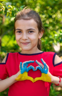 Portrait of smiling young woman standing against trees