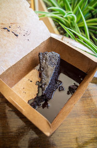 Chocolate cake slice with generous chocolate sauce in a takeaway box.