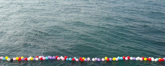 High angle view of multi colored balloons hanging over sea