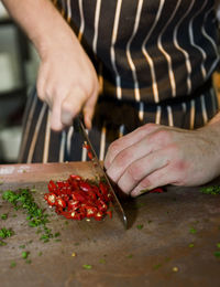 Close up of chef chopping red chili peppers at commercial kitchen