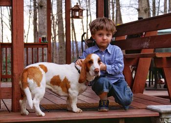 Portrait of boy with dog kneeling on hardwood floor