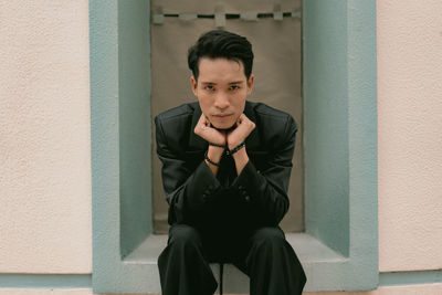 Portrait of young man standing against wall