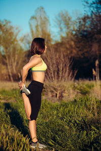 Woman exercising while standing by plants