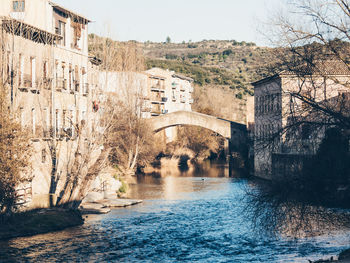 Arch bridge over river amidst buildings in city