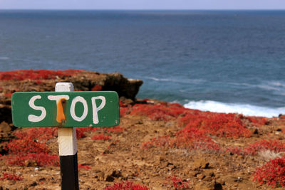 Close-up of sign by sea against sky