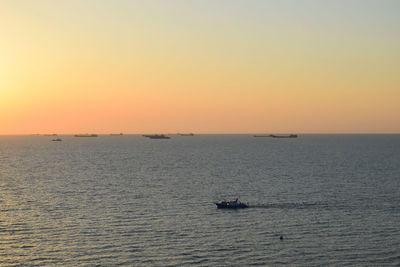 Boat sailing on sea against clear sky during sunset