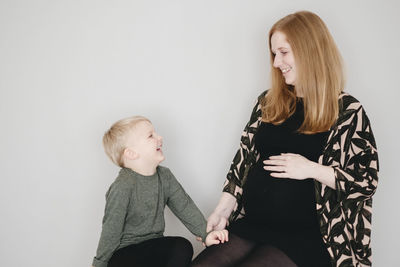 Mother and daughter sitting against wall