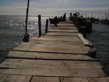 Wooden pier over sea against sky