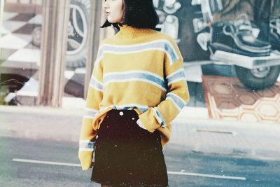 Rear view of woman standing on street in city