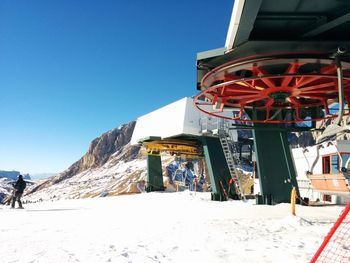 People on snow covered landscape against clear blue sky