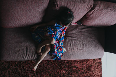 High angle view of girl sitting on sofa at home