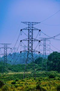 Electricity pylons on field against clear sky