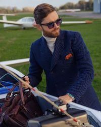 Young man wearing sunglasses standing by car