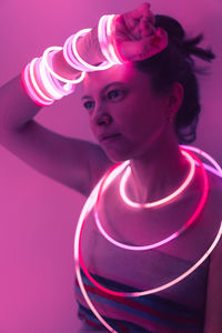 Portrait of woman standing against pink background