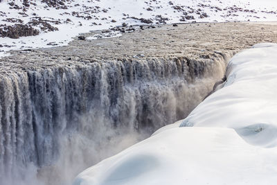 Scenic view of waterfall against snowcapped mountains