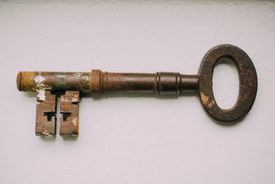 Close-up of old rusty metallic key against white background