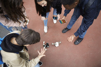 High angle view of friends gesturing during robot battle at park