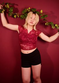 Midsection of woman standing against red background