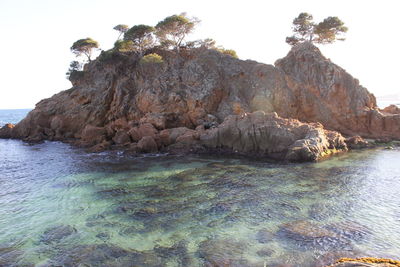 Rock formations in sea against clear sky