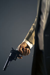 Midsection of man holding cigarette against white background