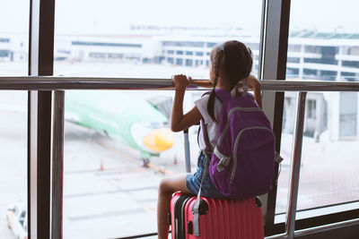 Rear view of girl sitting at airport