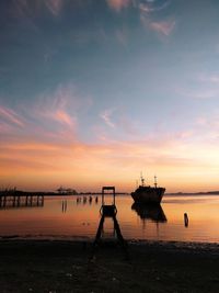 Silhouette boats in sea against sky during sunset