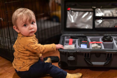 Portrait of cute boy sitting by tool box