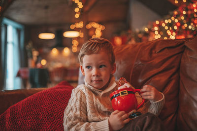 Portrait candid happy kid in knit beige sweater hold xmas mug with marshmallows and candy cane