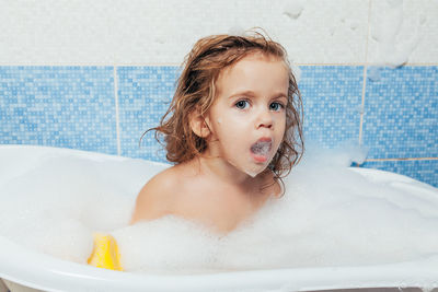 Cute shirtless girl sitting in bathtub at home