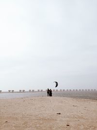 Rear view of people at beach against clear sky