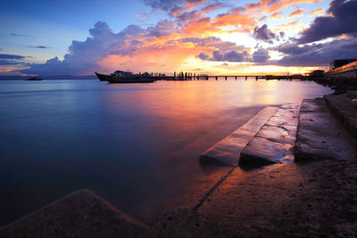 Boats on lake against cloudy sky during sunset