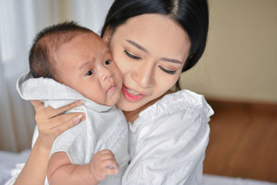 Mother embracing cute baby at home