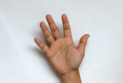 Close-up of human hand against white wall