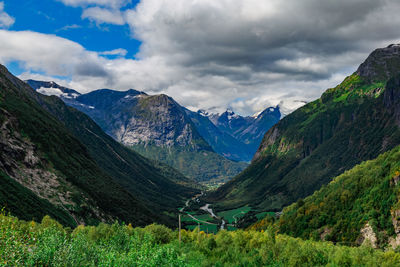 View from the road on a the valley between beautiful norwegian mountains against dramatic cloudy sky